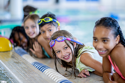 Kids leaning on the edge of the pool posing for a picture