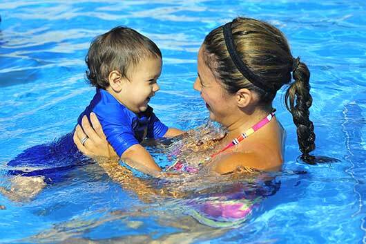 Swim instructor with a baby in a water babies swim class