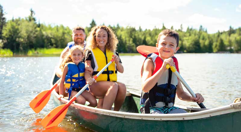 A family in a canoe with each person wearing a life jacket.